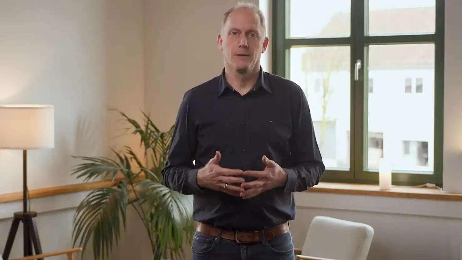 Ein Mann steht vor einer Sitzecke und spricht über Steuerthemen